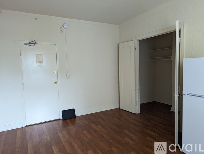 A room with a white door, a white wall, and a white fridge.