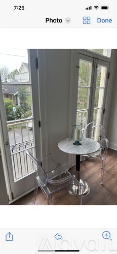 A white table with two chairs is in front of a glass door.