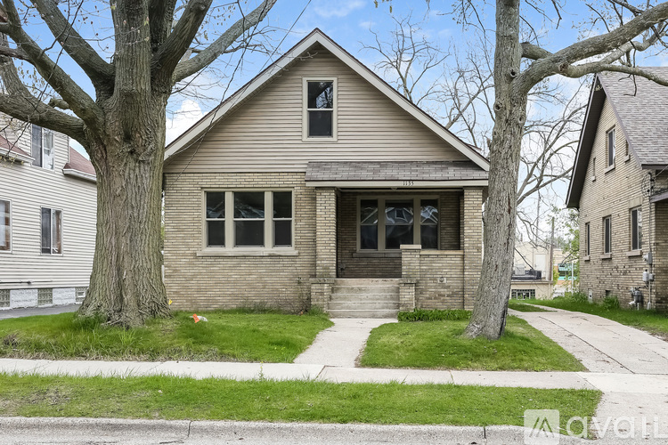 A house with a front yard and a tree in front of it.