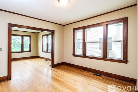 A room with wooden floors and two windows with blinds.