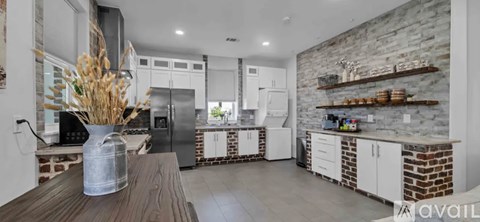 A kitchen with a wooden table and a vase of dried flowers on it.