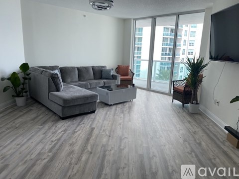 A living room with a grey couch and a television on the wall.