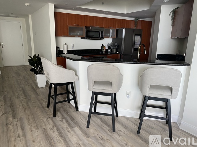A kitchen with white chairs and a black counter.