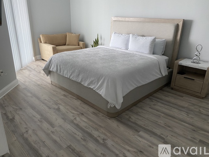 A bedroom with a large bed and a chair.