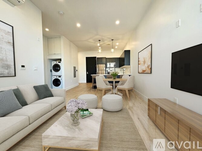 A modern living room with a grey sofa, a coffee table, and a dining area in the background.