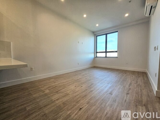 A spacious room with wooden flooring and a window.