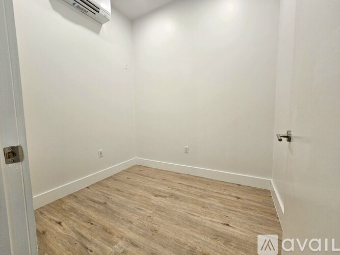 A room with wooden flooring and white walls.