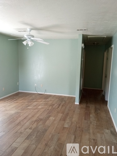 A room with a ceiling fan and wooden flooring.