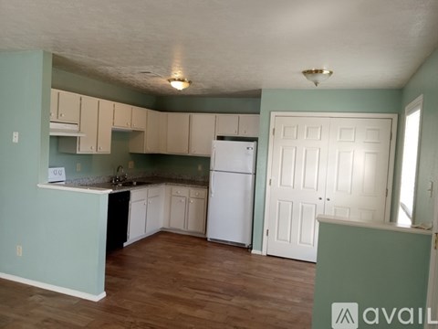 A kitchen with a white refrigerator and cabinets.