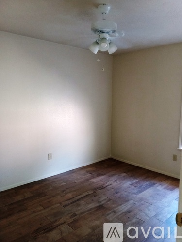 A room with wooden flooring and a ceiling fan.