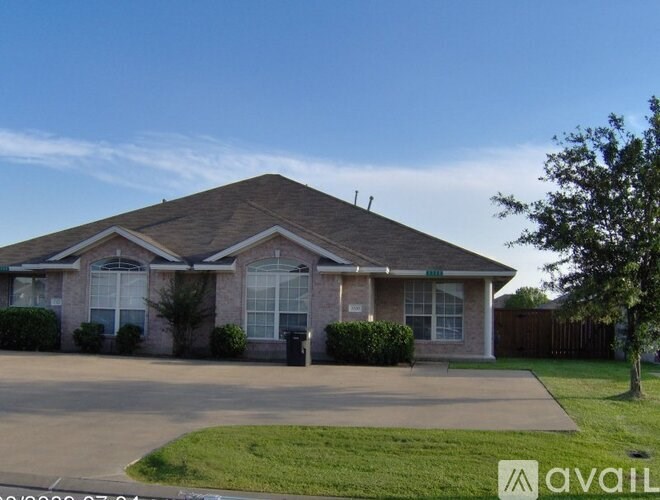 A house with a brown roof and a driveway in front.
