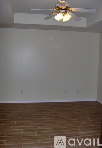A room with a ceiling fan and wooden flooring.
