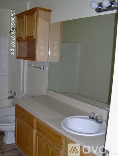 A bathroom with a toilet, sink, and wooden cabinets.