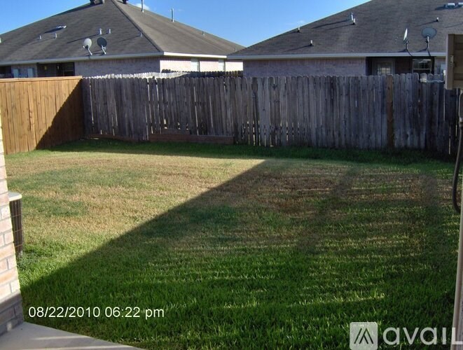 A backyard with a wooden fence and a house in the background.