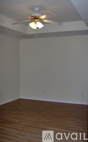 A room with a ceiling fan and wooden flooring.