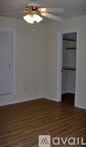 A room with a ceiling fan and wooden flooring.