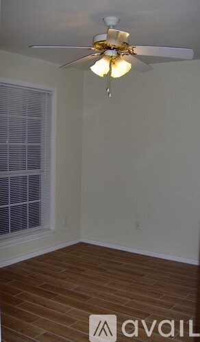 A room with a ceiling fan and wooden flooring.
