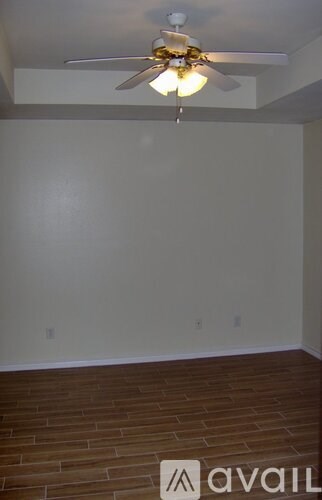 A room with a ceiling fan and wooden flooring.