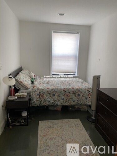 A bedroom with a bed, nightstand, and window.