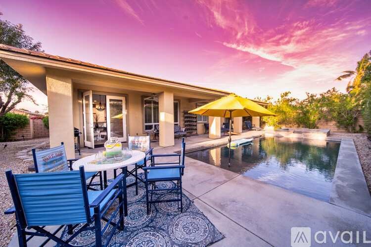 A patio with a table set for two and a pool in the background.