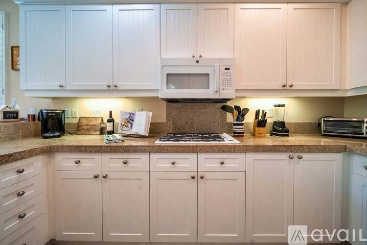 A kitchen with white cabinets and a granite countertop.