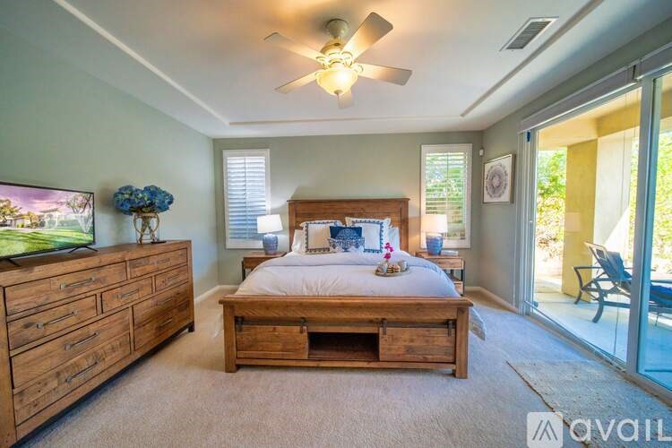 A bedroom with a bed, dresser, and sliding glass doors.