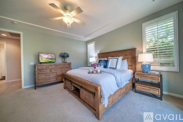 A bedroom with a large bed, a dresser, and a ceiling fan.