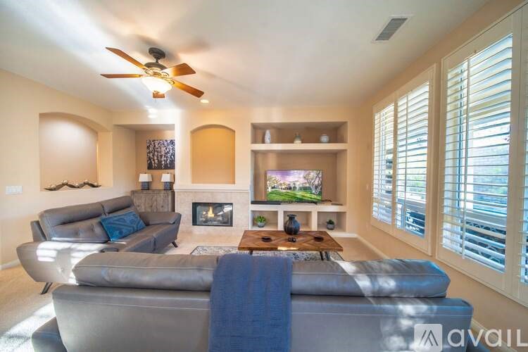 A living room with a grey couch and a fireplace.