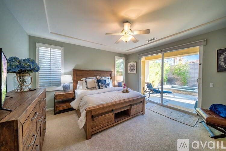 A bedroom with a bed, dresser, and sliding glass doors.
