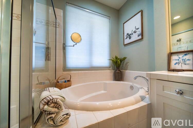 A bathroom with a white tub and a mirror on the wall.