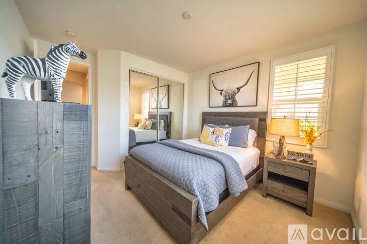 A bedroom with a bed, nightstand, and a zebra statue on a shelf.