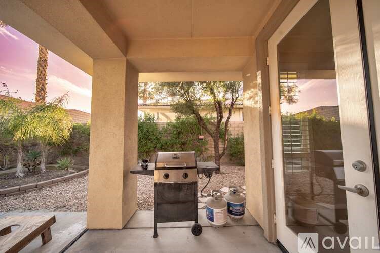 A patio with a grill and a container of charcoal.