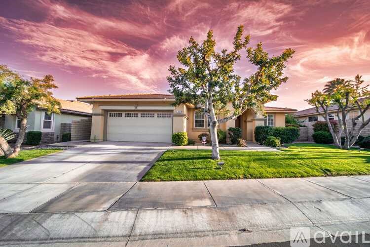 A house with a tree in front and a driveway leading to a garage.