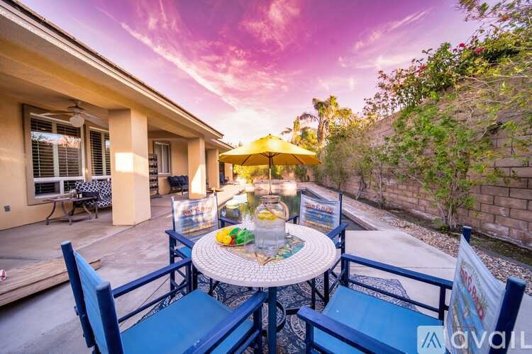 A patio with a table set for two and chairs with a sign that says "AVAILABLE".