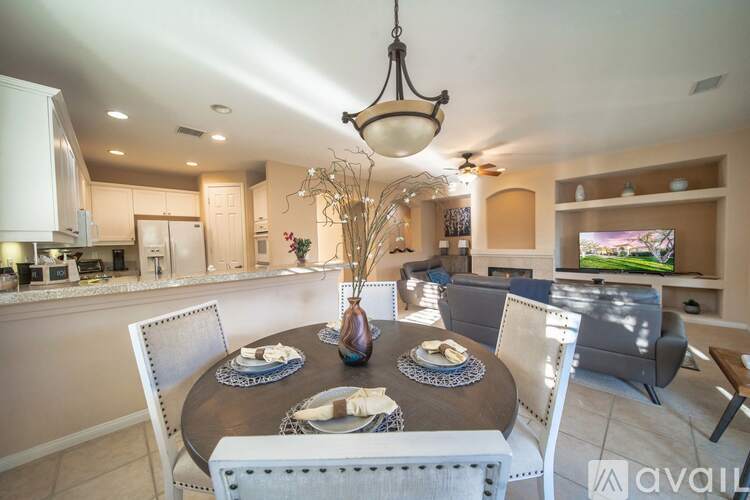 A dining room with a table set for two and a television in the background.