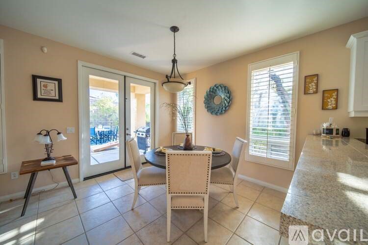 A dining room with a table set for two and a view of a patio through the door.