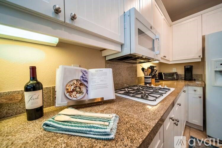 A kitchen with a wine bottle and a book on the counter.
