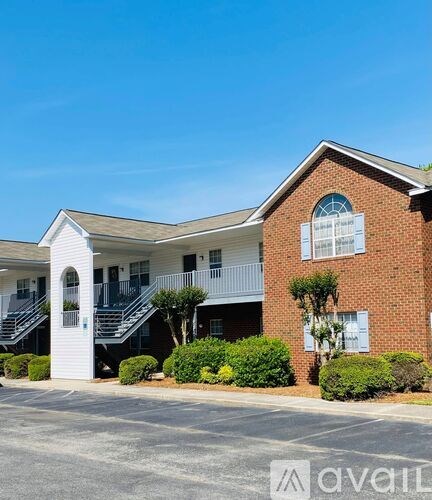 A brick building with a white entrance and a balcony.