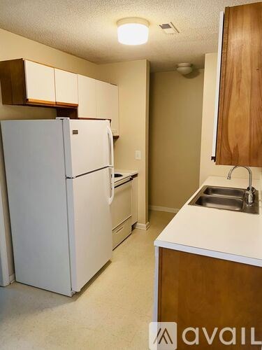 A small kitchen with a white refrigerator and a white sink.