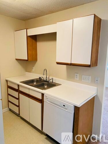 A kitchen with white countertops and brown cabinets.