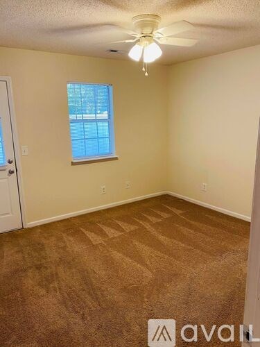 A room with a carpeted floor and a ceiling fan.