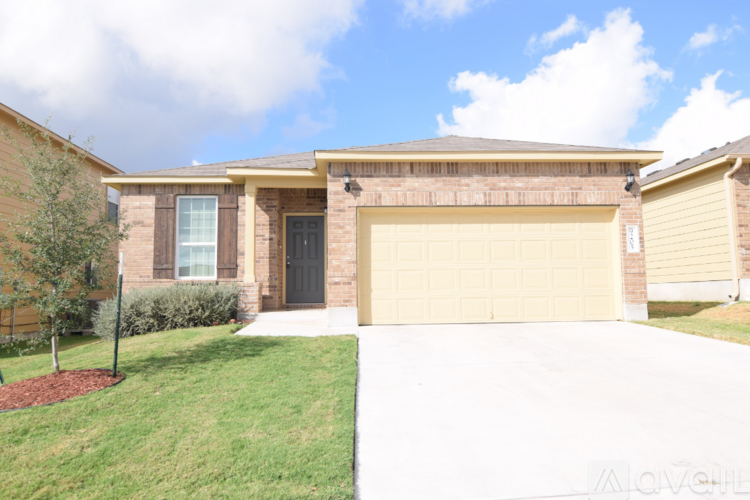 A house with a garage door and a tree in front.