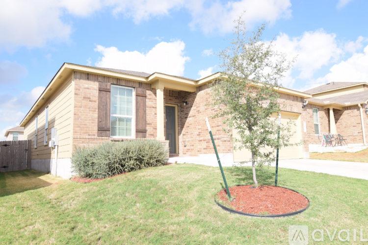 A house with a tree in a flower bed in front of it.