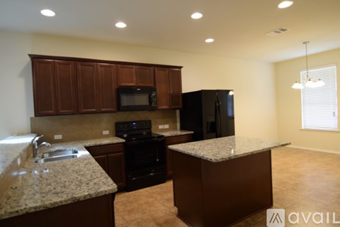 A kitchen area with a black refrigerator and brown cabinets.