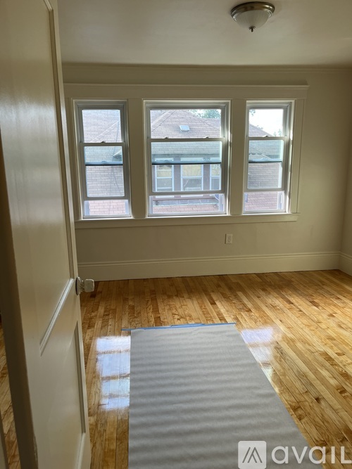 A room with wooden floors and a window overlooking a building.