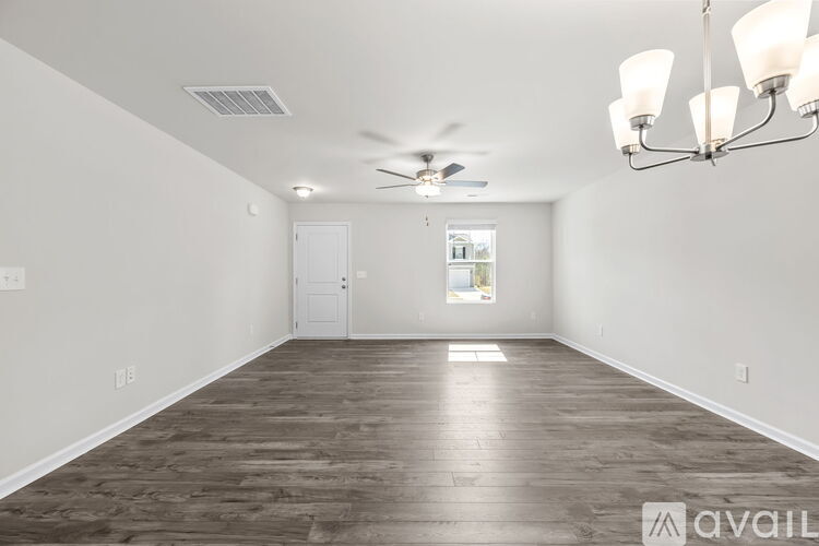 A spacious room with wood flooring and a ceiling fan.