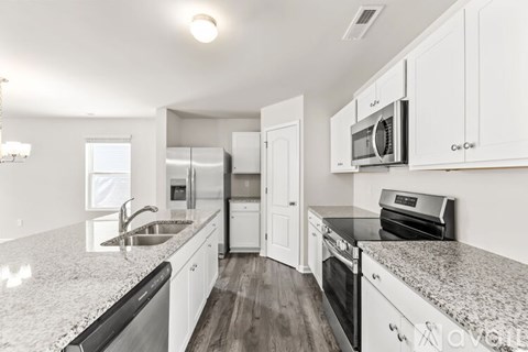 A kitchen with white cabinets and granite countertops.