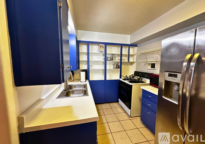 A kitchen with blue cabinets and a stainless steel refrigerator.