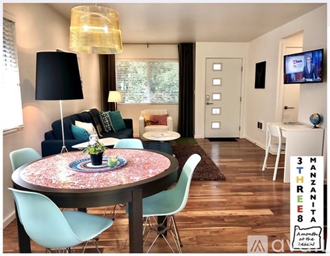 A living room with a round table and chairs, a sofa, a TV, and a window with blinds.