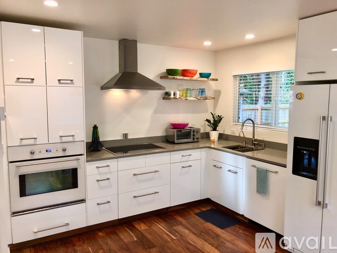 A modern kitchen with white cabinets and wooden floors.